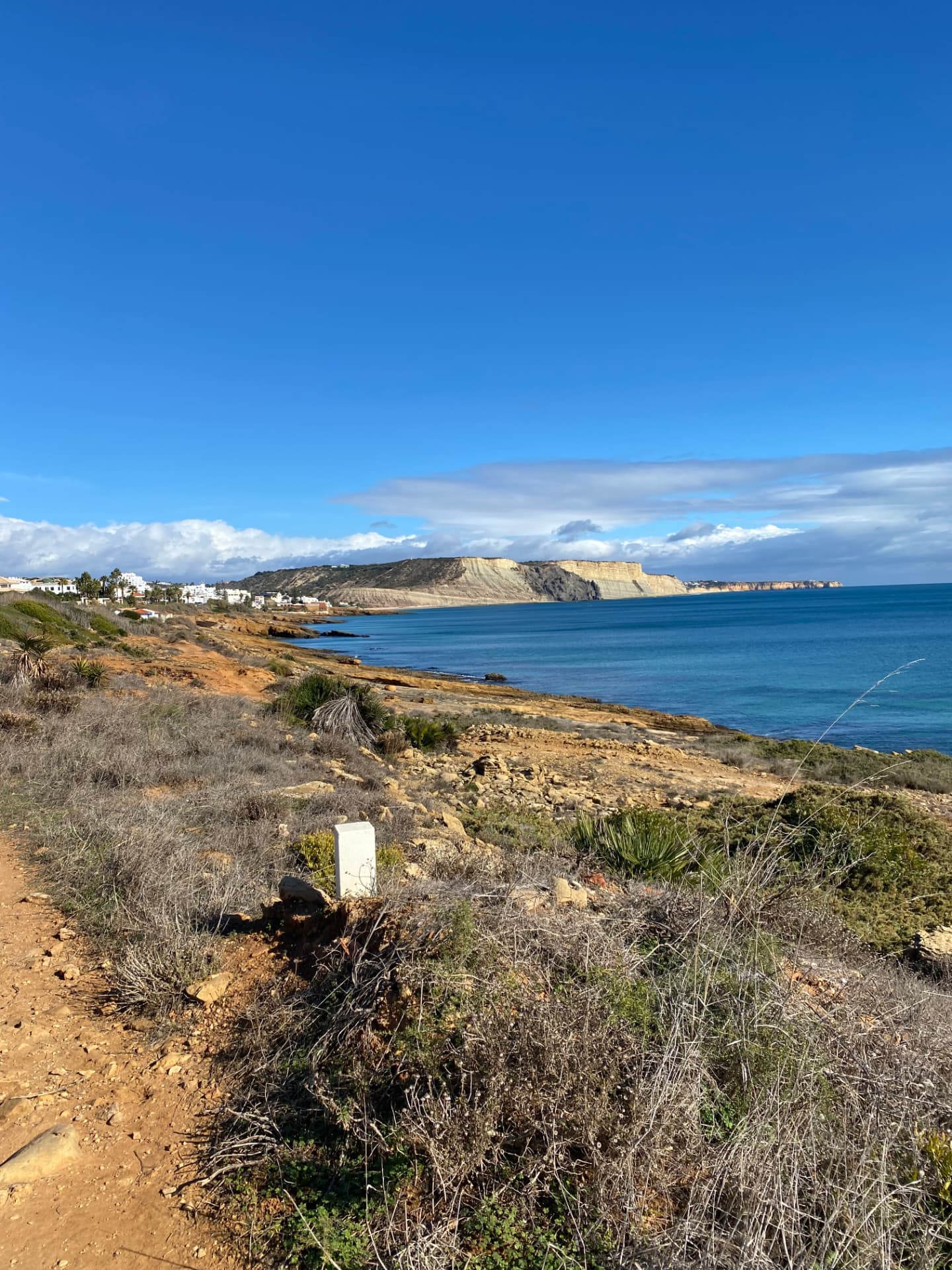 Coastal footpath above the sea looking back across the bay towards Luz and the cliffs