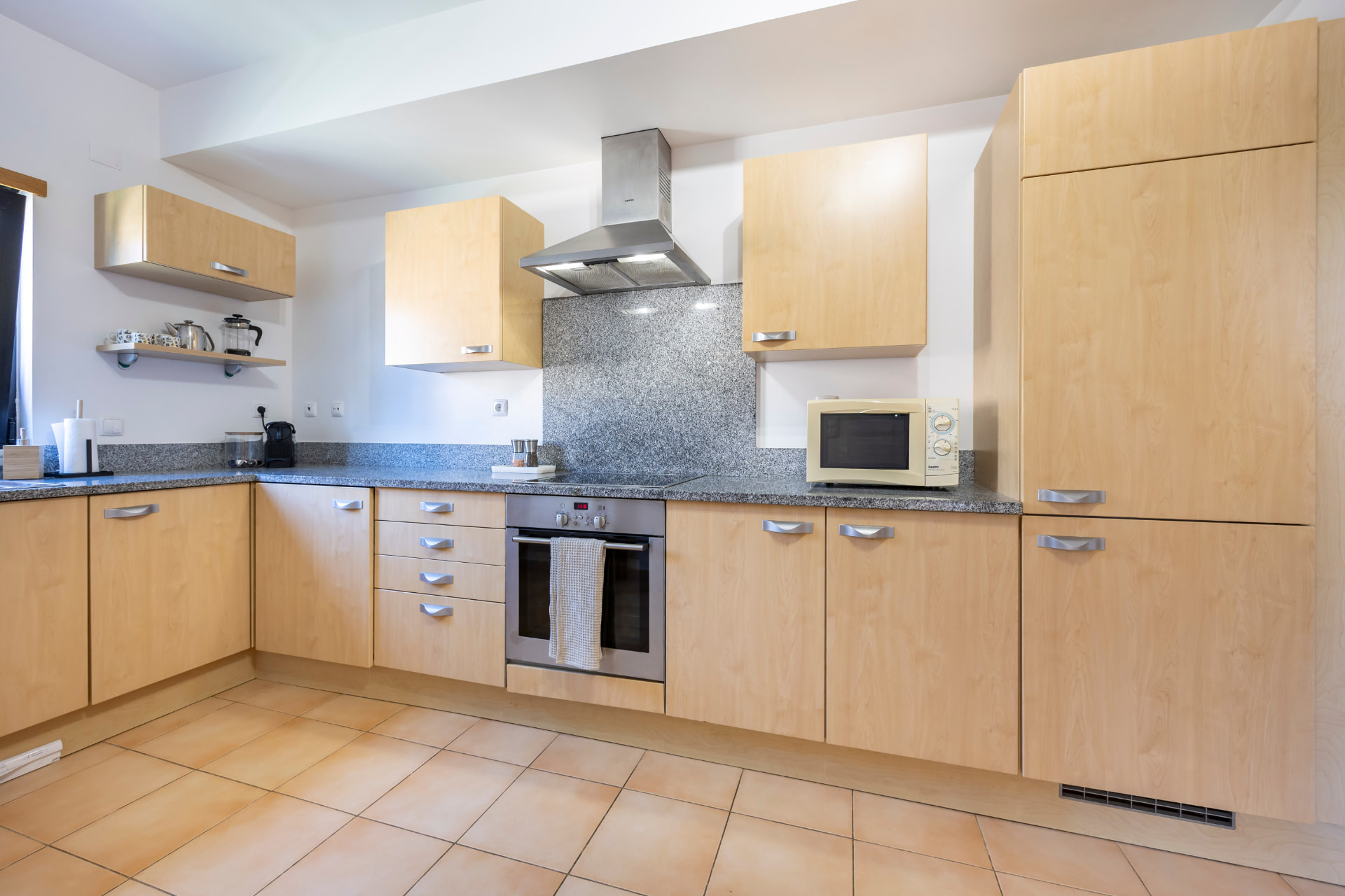 Full kitchen with wood cabinetry, granite worktops, oven, hob, extractor and microwave