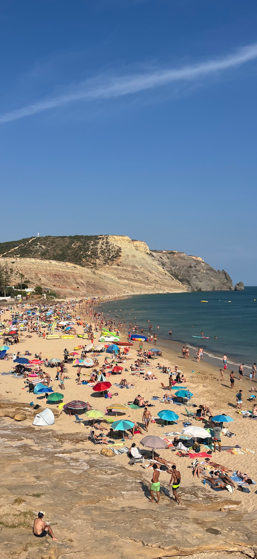 Praia da Luz beach filled with parasols, curving towards the Rocha Negra cliffs and turquoise water