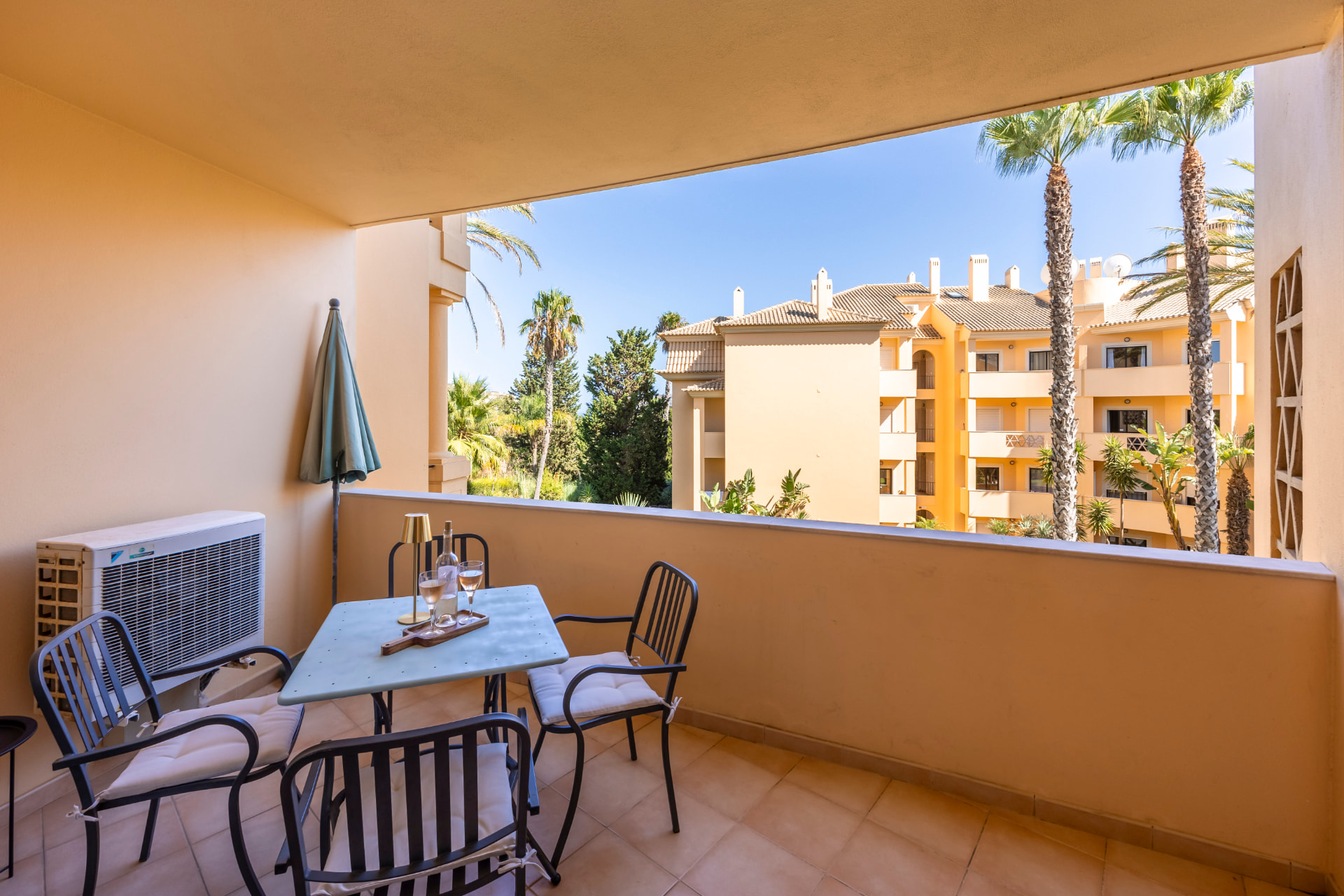 Terrace table set with glasses, looking out over palms and resort rooftops