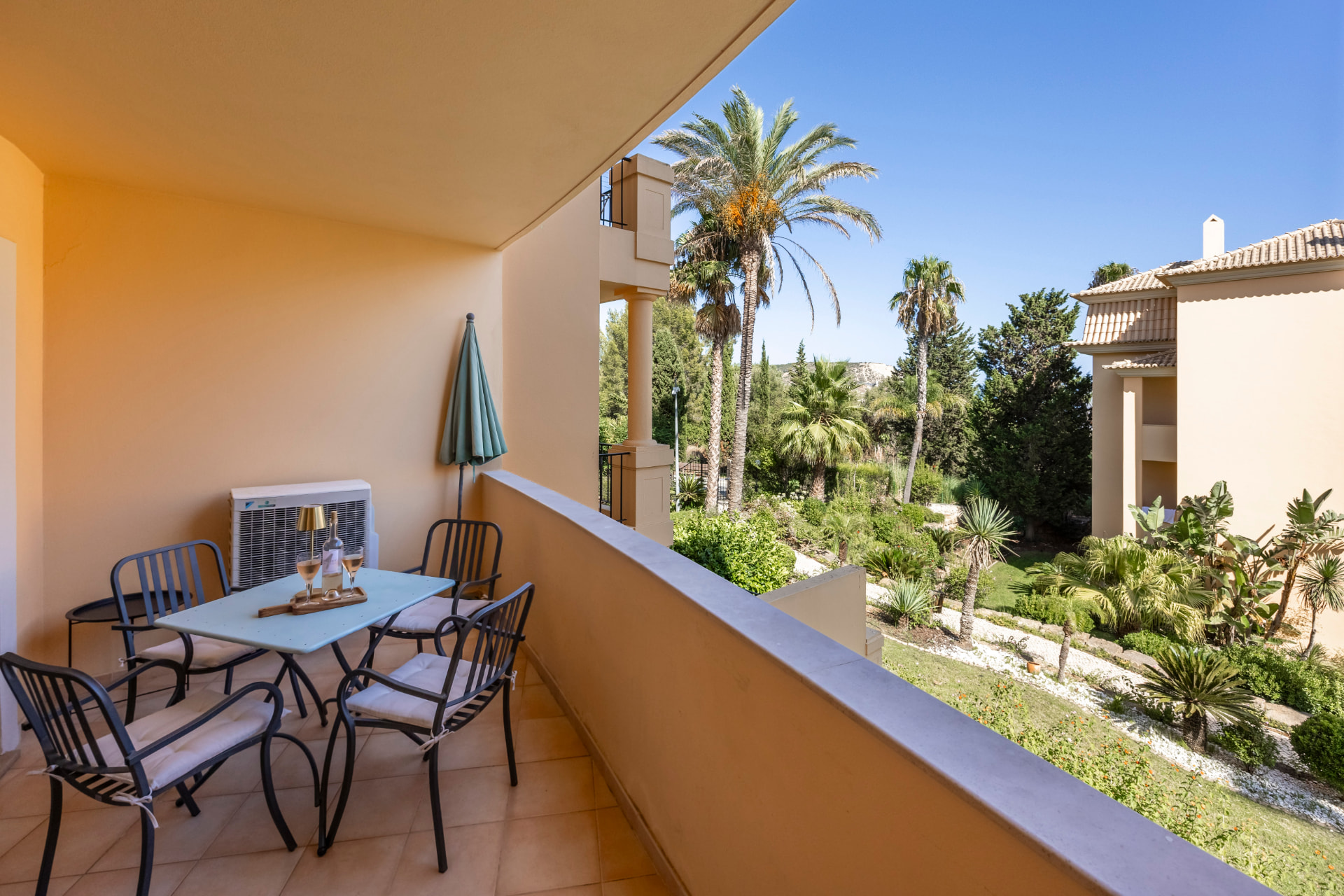 Large covered terrace with a table for four, a parasol and green garden views