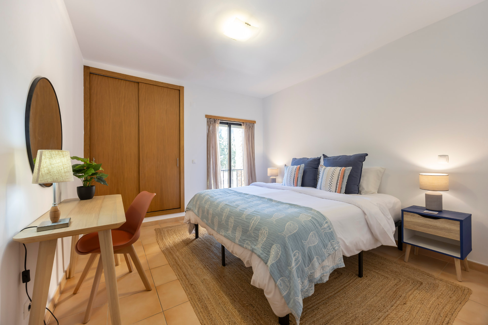 Bedroom with a made bed, two bedside lamps, wardrobe and a small writing desk