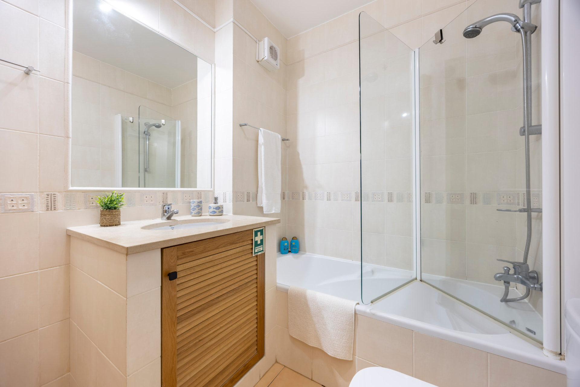 Bathroom with a large mirror, stone-topped vanity, bath and shower screen