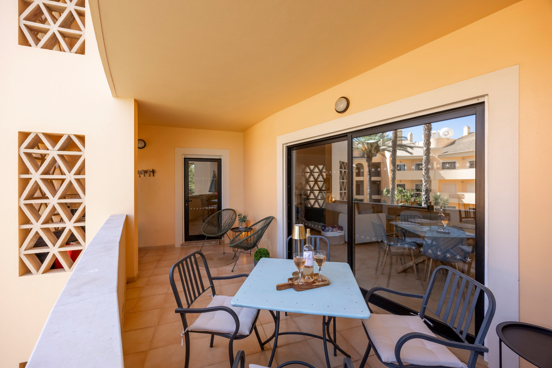 The covered terrace with a table set for drinks, looking back into the living area through glass doors